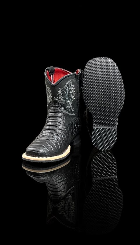 Black crocodile skin cowboy boot with red lining and cream sole, shown from side and bottom views against black background